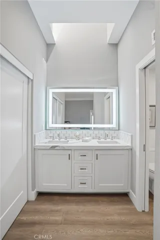 Updated bathroom featuring a dual-sink vanity, quartz countertops, and custom cabinetry. Includes a large illuminated mirror and modern finishes, creating a clean and elevated space.