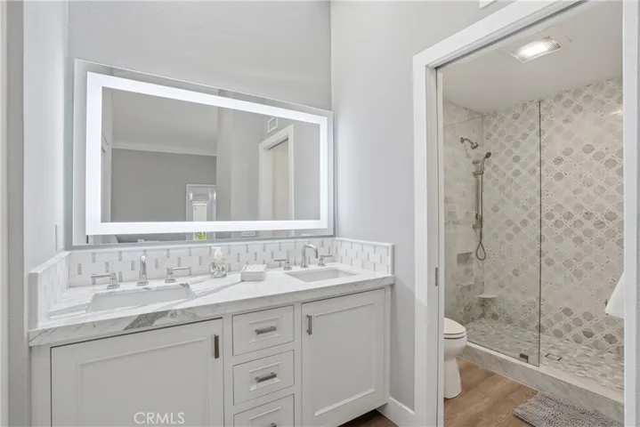 Beautifully upgraded bathroom with dual vanity, designer tilework, and a glass-enclosed walk-in shower. The cohesive finishes and spa-like design offer both functionality and style.