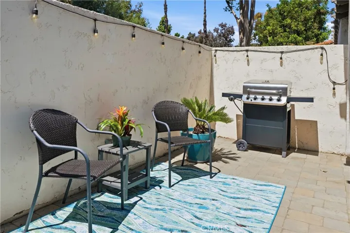 Private outdoor patio perfect for relaxing or entertaining, featuring paver flooring, string lighting, and space for seating and grilling. A low-maintenance outdoor retreat ideal for enjoying the Southern California lifestyle.