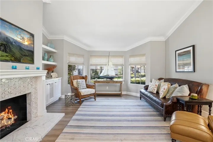 Spacious living room with vaulted ceilings, abundant natural light, and a cozy fireplace creating a warm focal point. Large windows frame the space while enhancing the bright, open feel, perfect for both everyday living and entertaining.