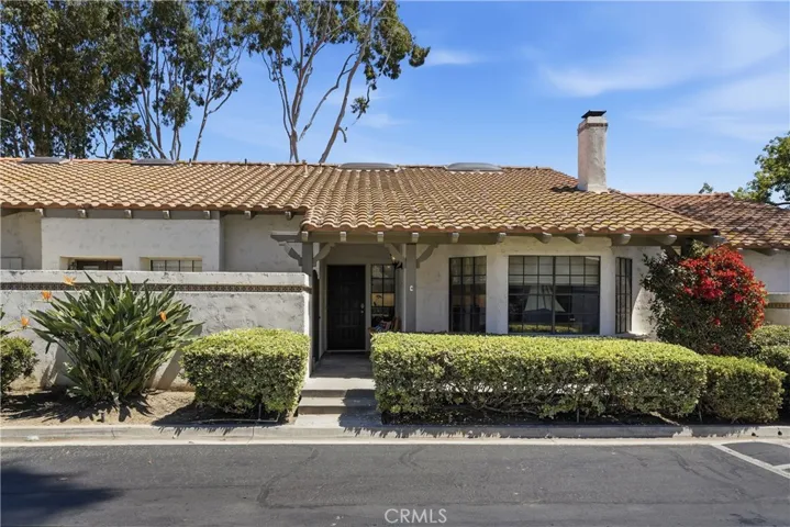 Inviting front entry featuring a covered porch, gated courtyard feel, and beautifully manicured greenery. The thoughtful landscapi