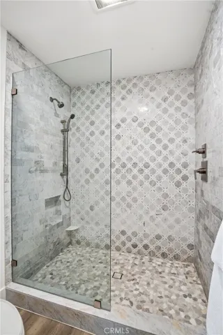Elegant walk-in shower featuring designer tilework, glass enclosure, and modern fixtures. The detailed tile design and spacious layout create a refined, spa-like atmosphere.