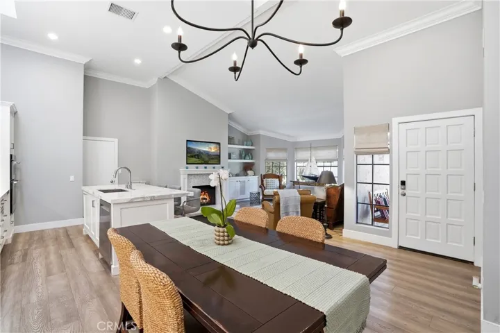 Open-concept living showcasing seamless flow from dining area to kitchen and living room. Vaulted ceilings, abundant natural light, and cohesive finishes create a bright and inviting space ideal for both entertaining and everyday living.