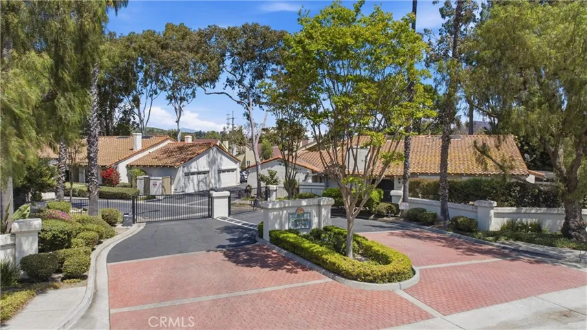 Secure gated community entrance with beautifully maintained landscaping and charming Spanish-style architecture. Offers added privacy and a welcoming neighborhood feel.