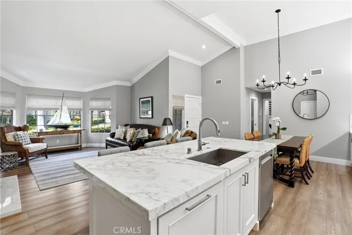 Open-concept kitchen overlooking the living room, featuring a large center island with sink, quartz countertops, and abundant cabinetry. Designed for connection and flow, this layout allows for effortless entertaining and everyday living.