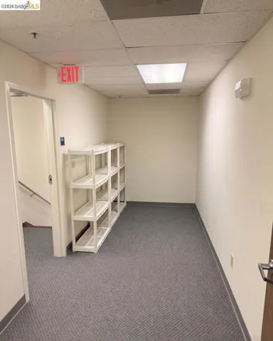 hall featuring a paneled ceiling and dark carpet