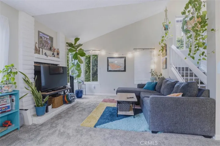 Living room w/vaulted ceilings and a gas fireplace (behind the TV). Brand new carpet and lots of natural light.