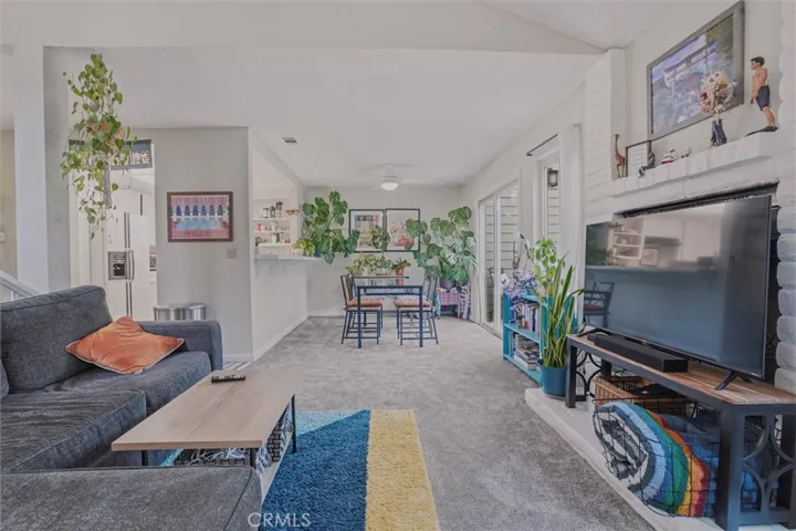 Living room looking back at the dining area w/sliding door to backyard on the right and kitchen bar to the left.  Gas fireplace is behind their TV