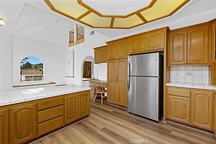 Kitchen view with new refrigerator and ample cabinets and working areas.