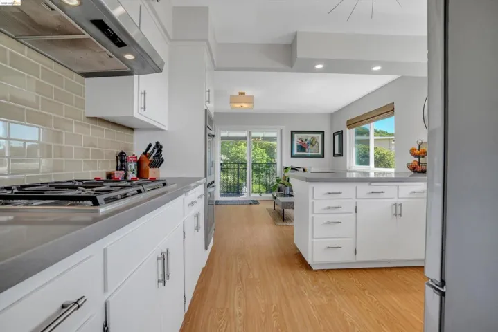 Kitchen featuring stainless steel appliances, extractor fan, white cabinetry, light wood finished floors, and recessed lighting