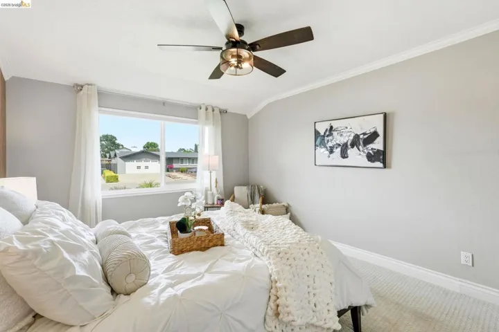 Bedroom with vaulted ceiling, crown molding, carpet flooring, and a ceiling fan