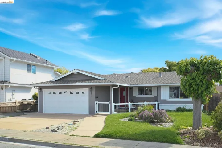 Ranch-style home with a garage, driveway, covered porch, and a shingled roof