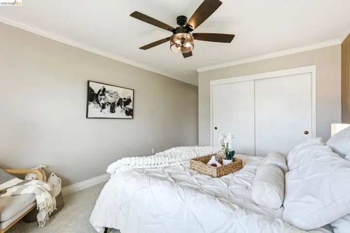 Bedroom featuring carpet, ornamental molding, ceiling fan, and a closet
