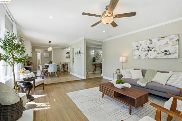 Living room featuring light wood-style flooring, a ceiling fan, recessed lighting, and crown molding
