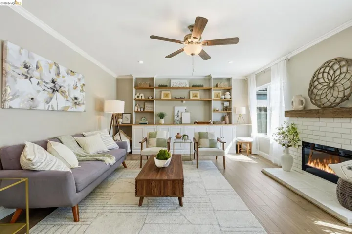 Living room with ornamental molding, ceiling fan, light wood-type flooring, a fireplace, and recessed lighting