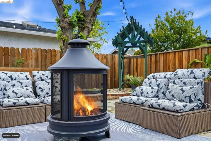 Fenced backyard with an outdoor living space with a fireplace and a patio
