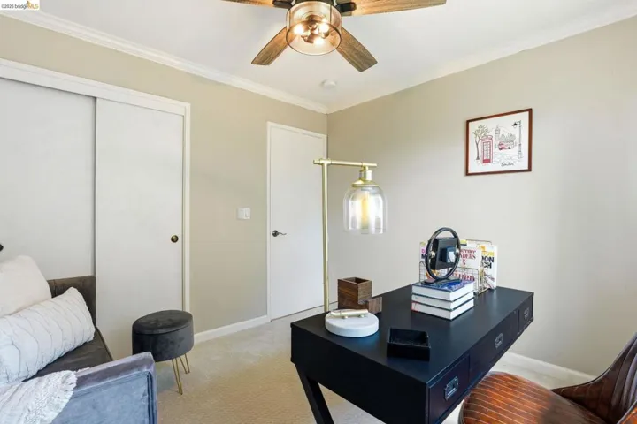 Carpeted home office with crown molding and a ceiling fan