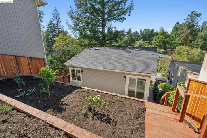 Rear view of property featuring a shingled roof and view of scattered trees