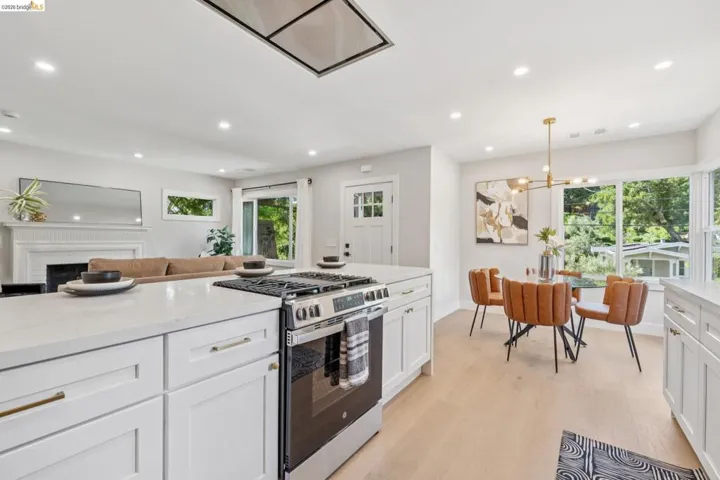 Kitchen featuring stainless steel gas range oven, light stone counters, white cabinets, and light wood-type flooring