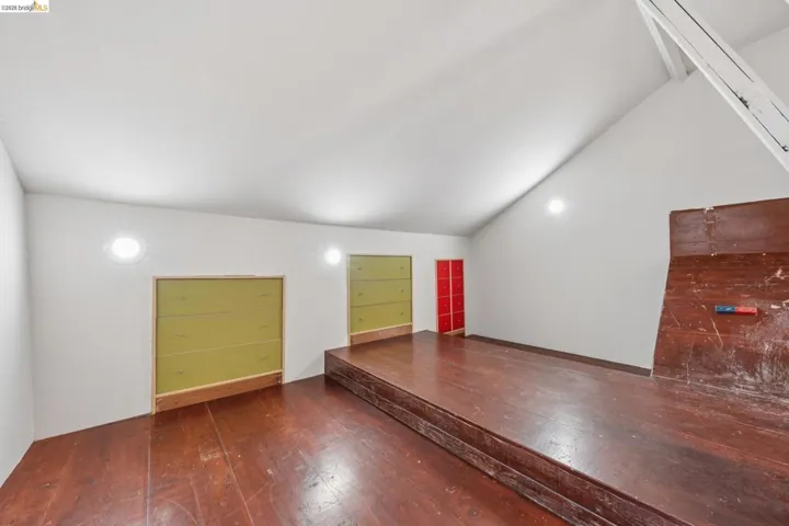 Additional living space featuring lofted ceiling and dark wood-type flooring