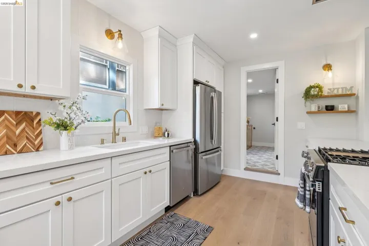 Kitchen featuring stainless steel appliances, white cabinets, light wood-style flooring, light stone countertops, and recessed lighting