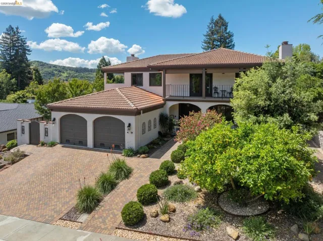 Mediterranean / spanish-style house with a chimney, an attached garage, a balcony, and decorative driveway