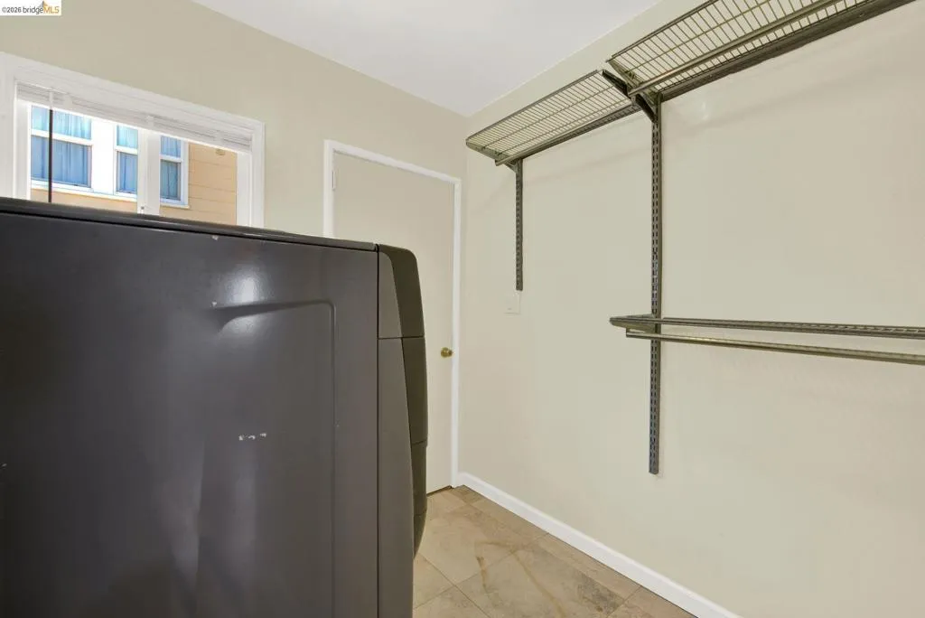 Walk in closet with washer / dryer and light tile patterned flooring