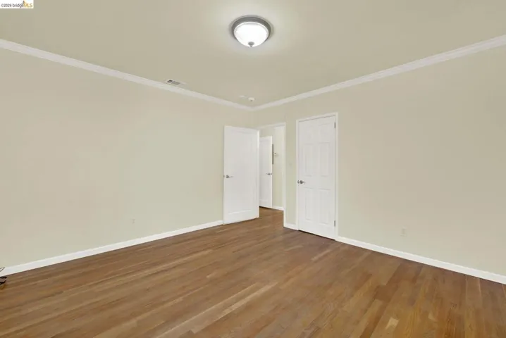 Empty room featuring dark wood-style flooring and ornamental molding
