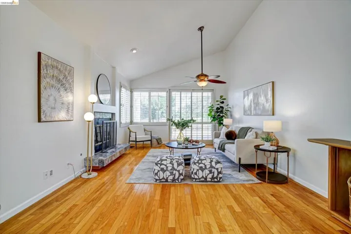 Vibrant hardwood flooring complements the fireplace with a stone surround