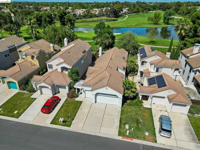 Aerial perspective of suburban area featuring a nearby body of water and a local golf course