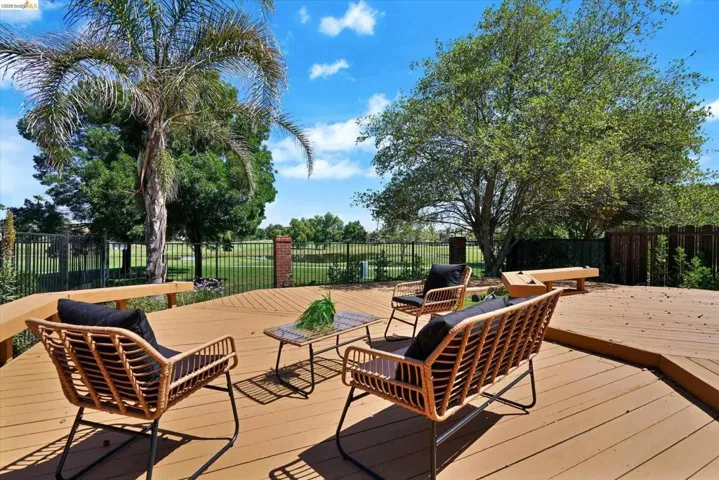 Expansive wood-finish deck with built-in bench seating, bordered by a black metal fence