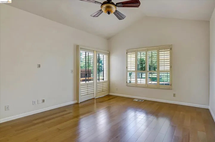 Unfurnished room featuring ceiling fan, wood-type flooring, and vaulted ceiling