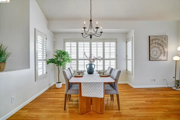 Dining area featuring rich wood-finish flooring and a central chandelier