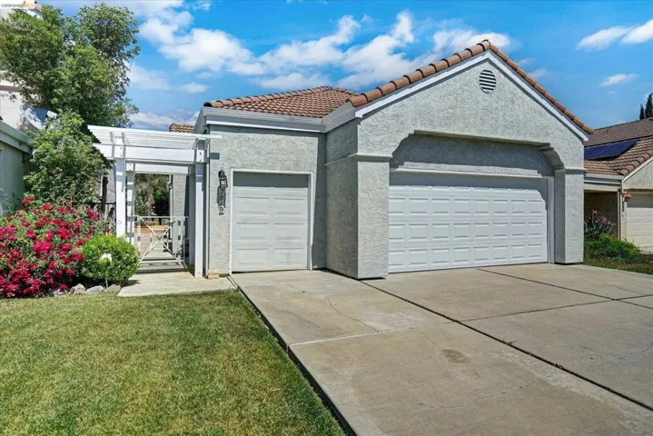 Mediterranean / spanish home featuring an attached garage, driveway, stucco siding, and a tile roof