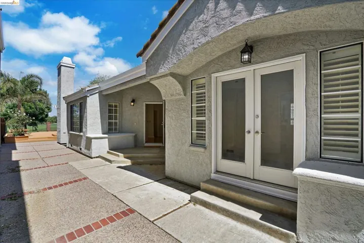 View of exterior entry with french doors, stucco siding, and a patio area