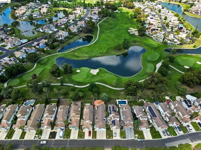 Aerial view of property's location with nearby suburban area, a nearby body of water, and a golf course