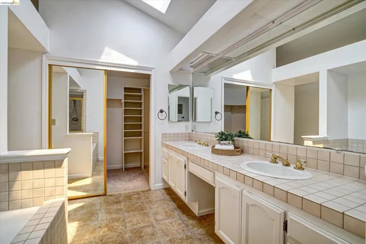 Double vanity with tile countertop, integrated sinks, and ample storage cabinetry