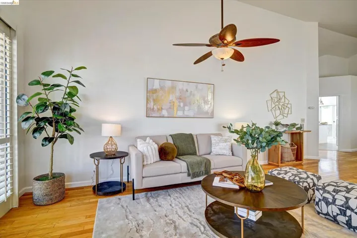 Living area featuring a vaulted ceiling and a ceiling fan with light fixture