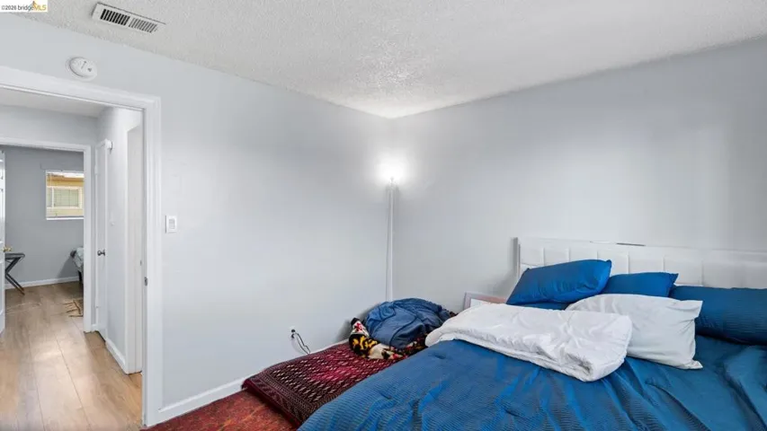 Bedroom with wood finished floors and a textured ceiling
