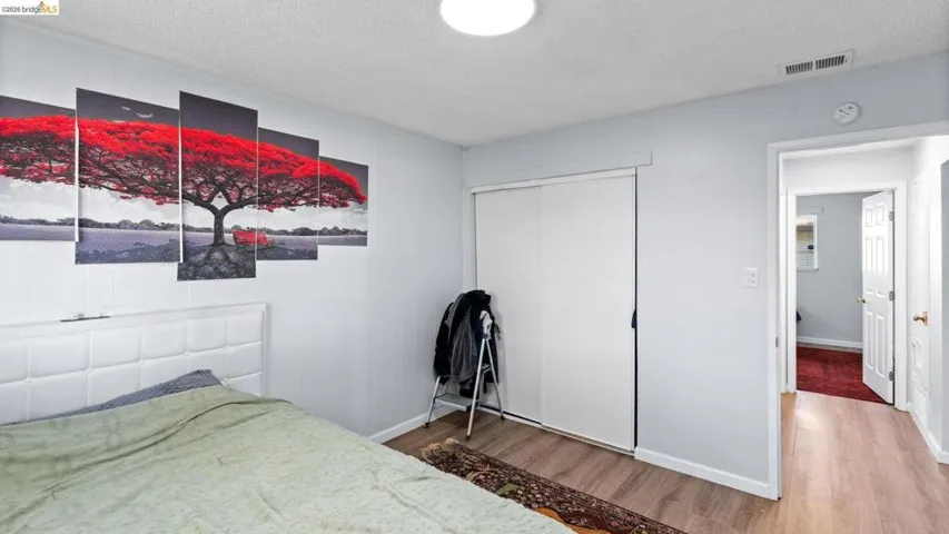 Bedroom featuring a textured ceiling, wood finished floors, and a closet