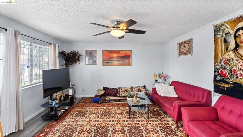 Living room with a ceiling fan, wood finished floors, and a textured ceiling
