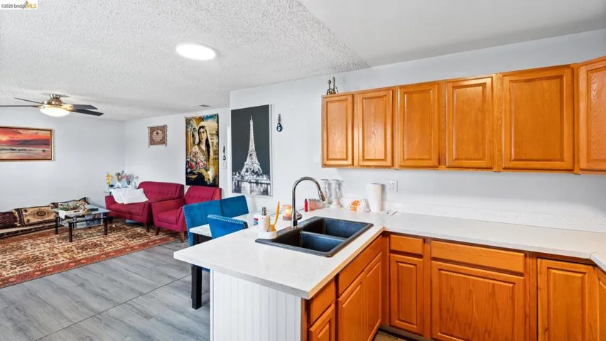 Kitchen with a peninsula, open floor plan, wood finish cabinets, a ceiling fan, and a textured ceiling
