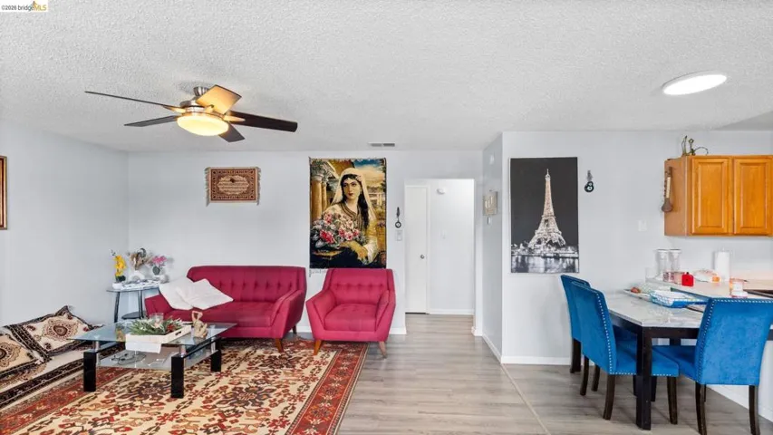 Living room featuring ceiling fan, a textured ceiling, and light wood-style flooring