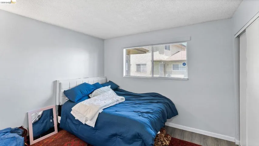 Bedroom with a textured ceiling, wood finished floors, and a closet