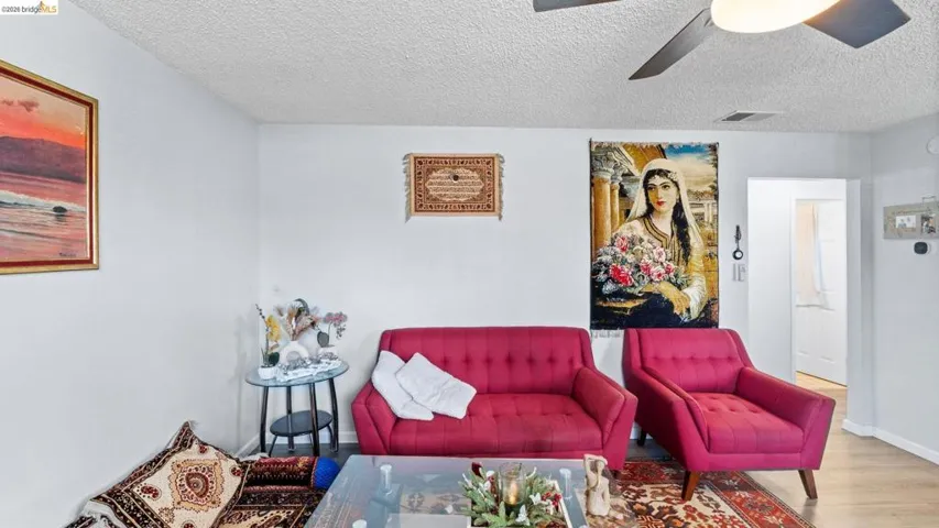 Sitting room with a textured ceiling, ceiling fan, and wood finished floors