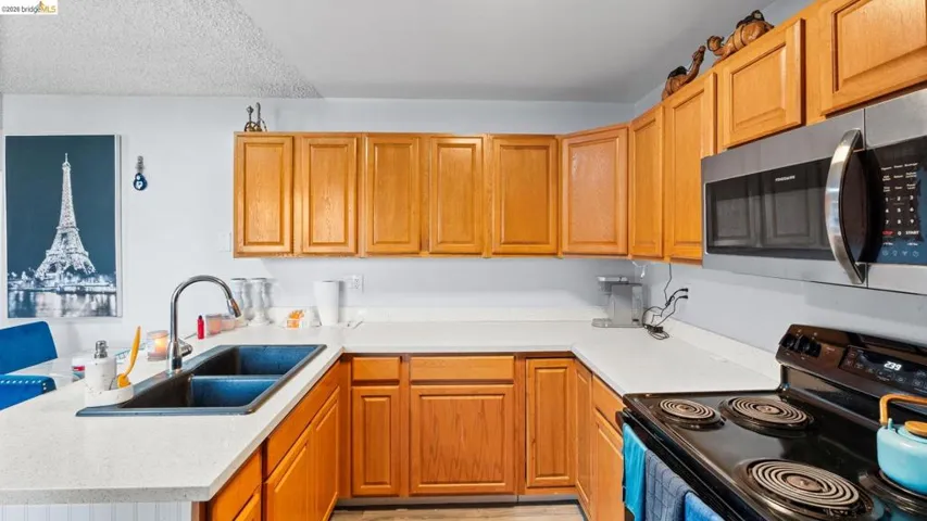 Kitchen with black electric range oven, stainless steel microwave, light countertops, and a peninsula
