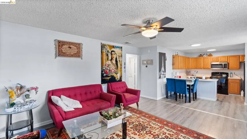 Living area featuring ceiling fan, light wood-style flooring, and a textured ceiling