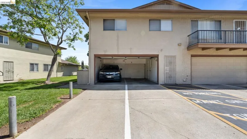 View of front facade featuring a balcony, a front lawn, and stucco siding