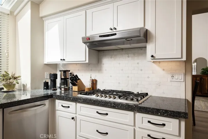 The kitchen features beautiful backsplash tiles, stovetop, and under-cabinet lighting.