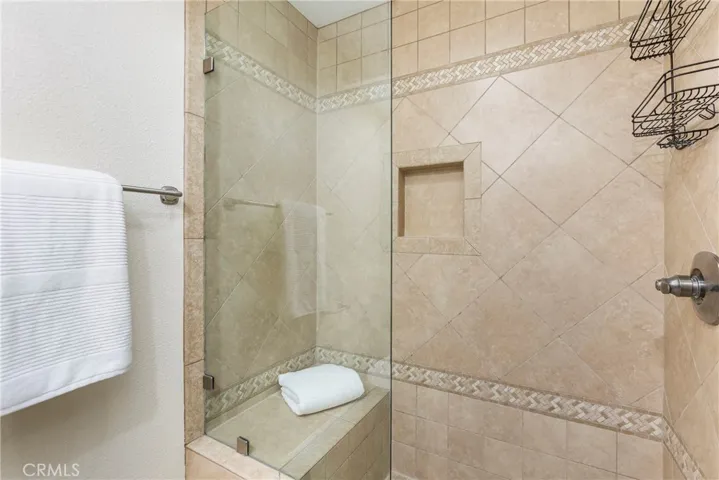 Secondary shower with seat and frameless glass door